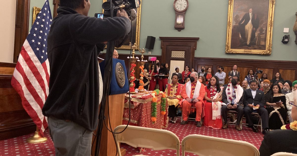 Journalist points camera at the audience of a New York City Council Diwali celebration.